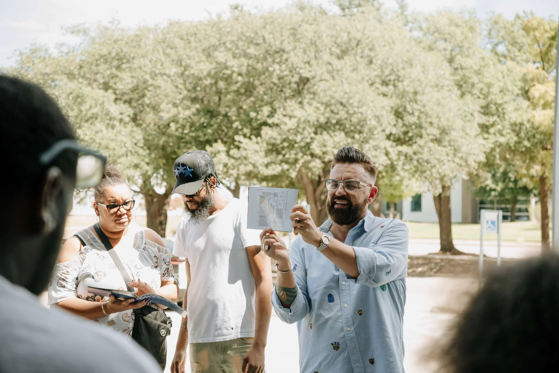 Pastor Ben showing the floor plan to a small group outside the building